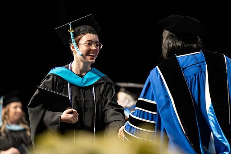 Person receiving a Master of Education diploma at GVSU commencement